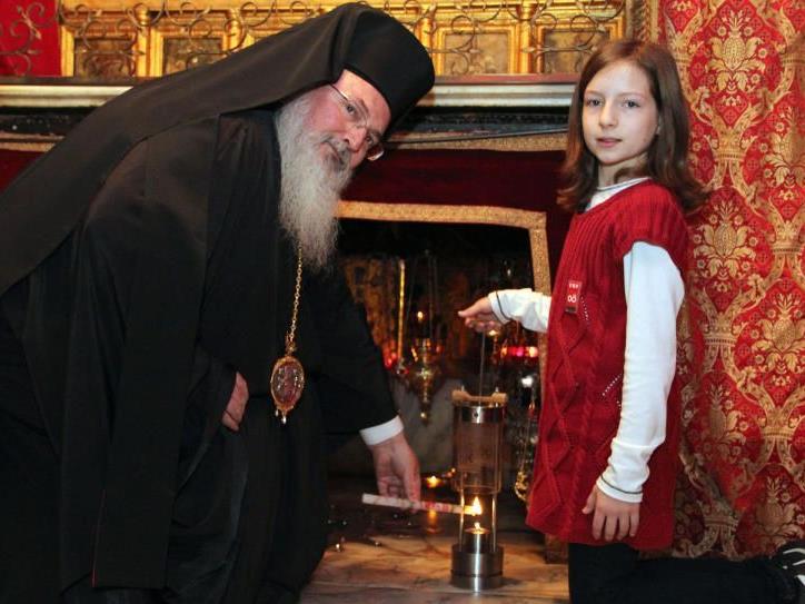 Die 11-jährige Sarah Schinwald aus Munderfing im Bezirk Braunau übernahm am Montag, 21. November 2011, in der Geburtsgrotte in Bethlehem das Friedenslicht vom griechisch-orthodoxen Bischo Theofilaktos (r.).