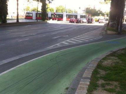 Auf den grünen Radwegen sind schwarze Spuren sichtbar.