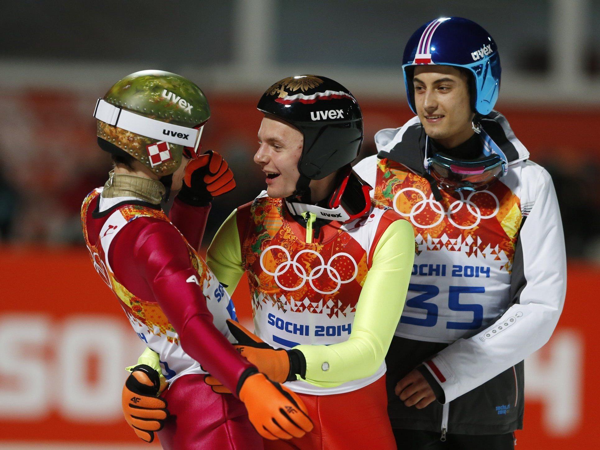 Kamil Stoch (im Bild mit deinen Teamkollegen) gewinnt die Goldmedaille auf der Normalschanze.