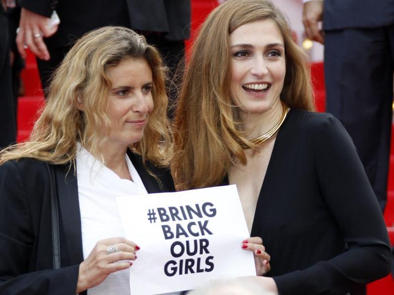 Die Französische Regisseurin Lisa Azuelos (l) and Schauspielerin Julie Gayet (r) mit dem Schriftzug '# Bring Back Our Girls'.