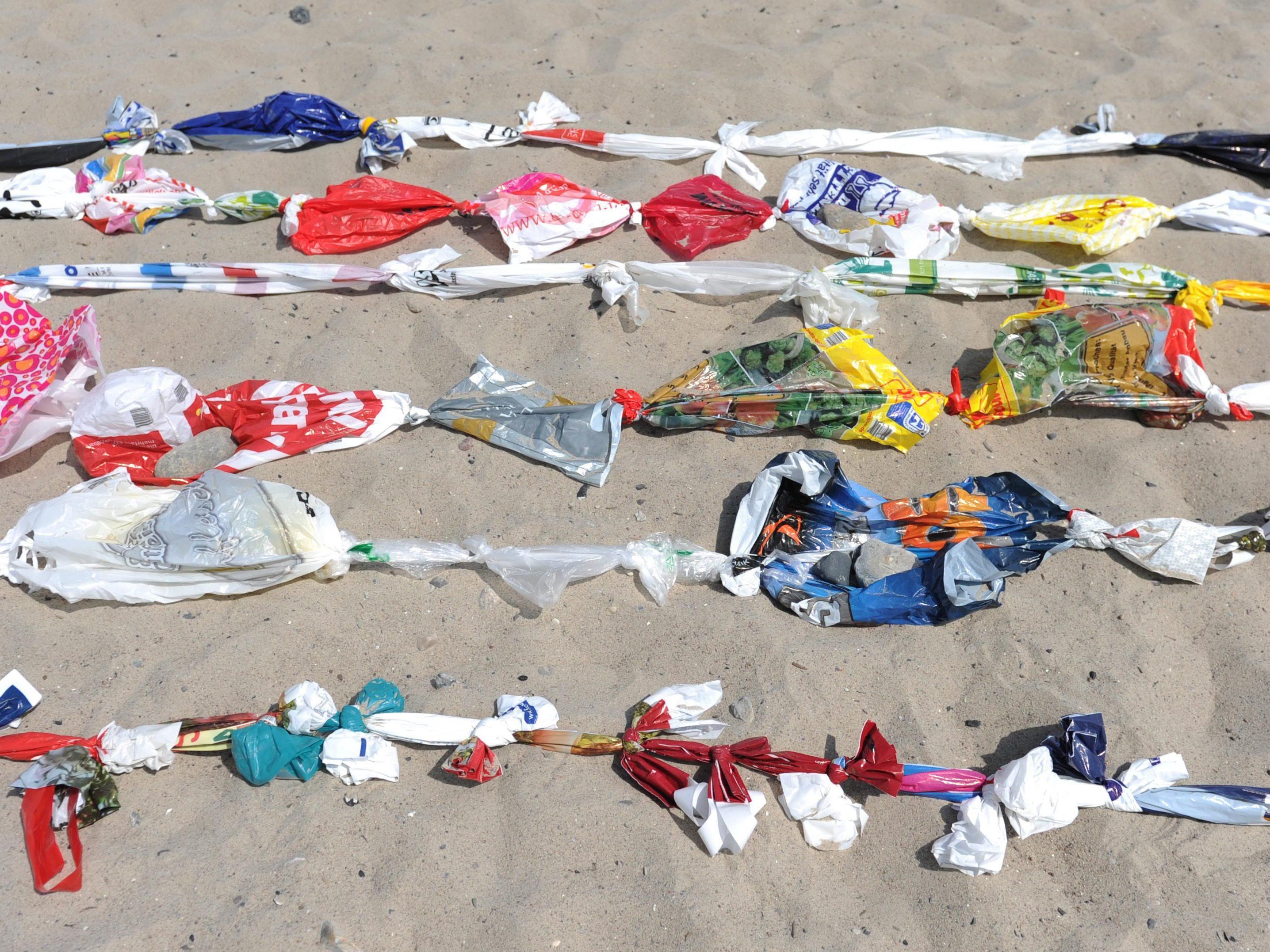 Aneinandergeknotete Plastiksackerl an einem Strand in Deutschland.