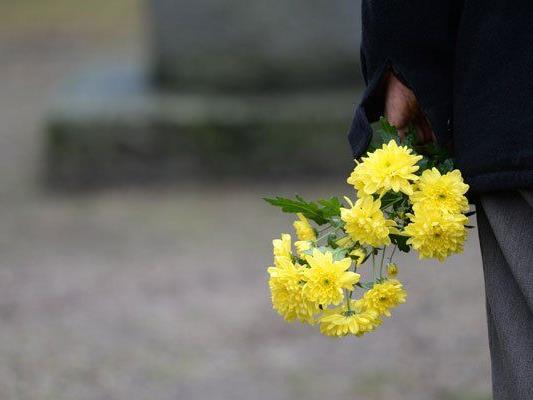 Mit einem Strauß Blumen gedenkt ein Mann den Opfern des NS-Regimes.
