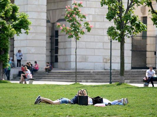 Menschen genießen am Dienstag die sommerlichen Temperaturen bis 28 Grad auf einer Wiese am Heldenplatz in Wien