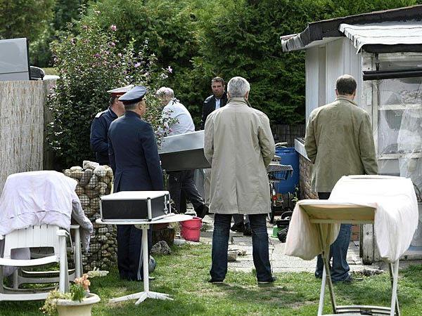 Die Ermittler bei der kriminalpolizeilichen Untersuchung im Garten des Hauses, in dem die Leichen gefunden wurden