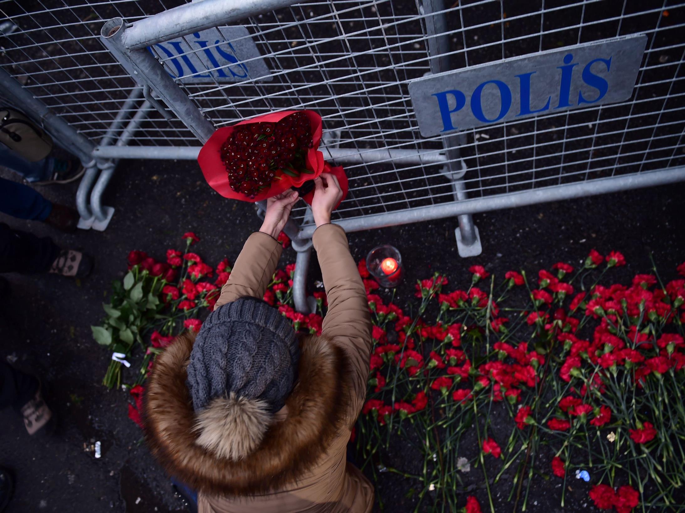 Passanten legen unweit des Tatorts Blumen nieder. Der Täter ist derweil weiterhin auf der Flucht.